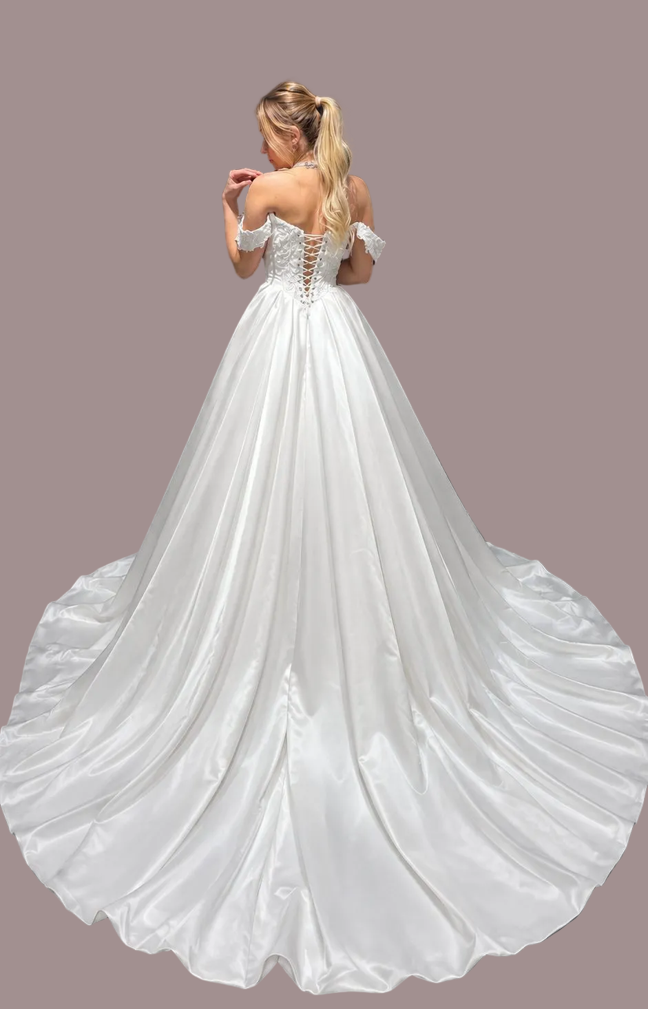 a white off-the-shoulder ball gown wedding dress is photographed from the back. The dress has lace-up back detailing and a full satin train.