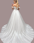 a white off-the-shoulder ball gown wedding dress is photographed from the back. The dress has lace-up back detailing and a full satin train.