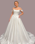  An off-the-shoulder white satin ball gown with a structured lace bodice with beaded detail and a full train against 