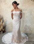 An off-the-shoulder lace wedding gown with a structured corset bodice and a long train