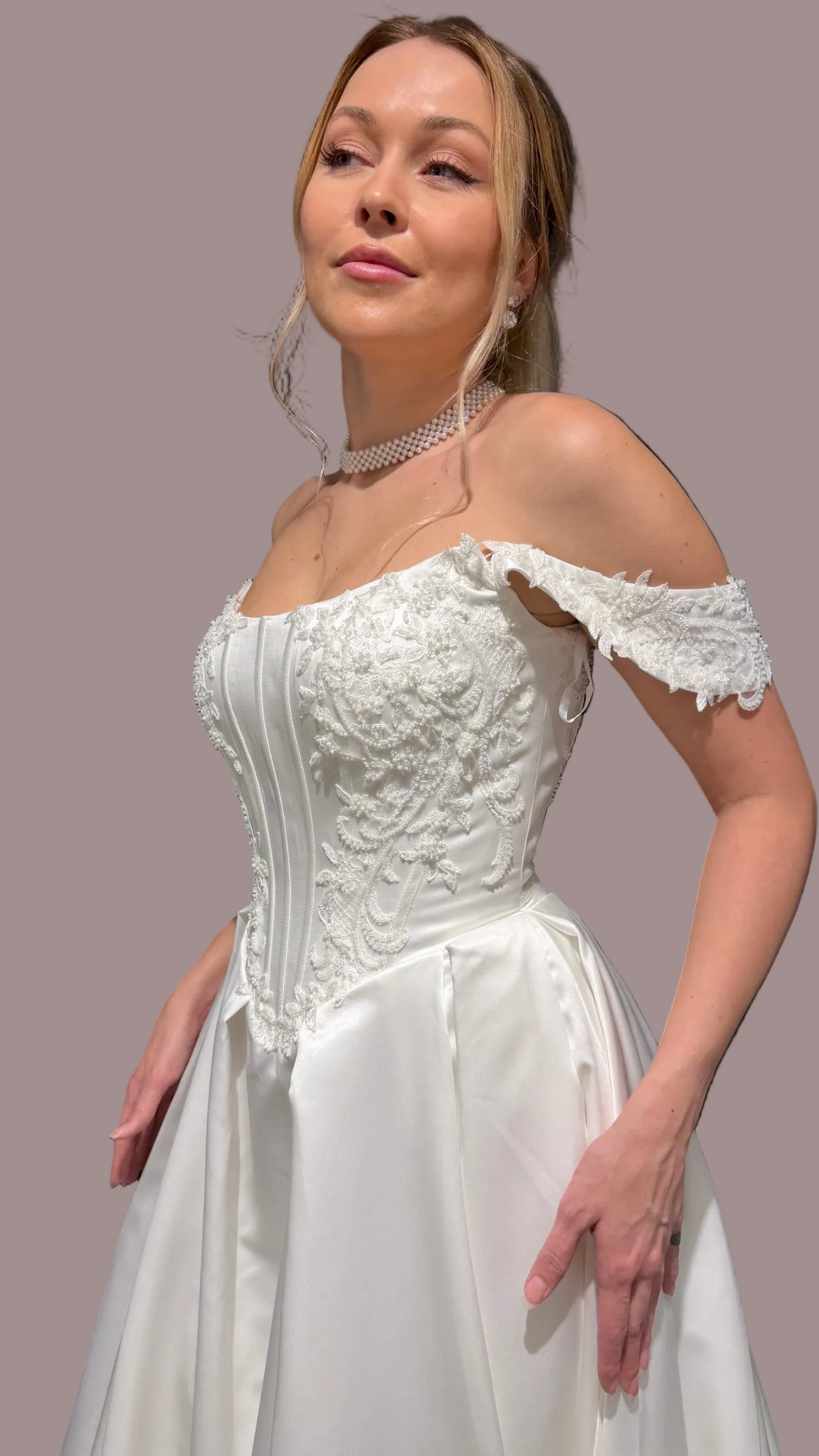 an off-the-shoulder white wedding gown with a structured lace beaded corset bodice and a full satin skirt, 