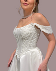 an off-the-shoulder white wedding gown with a structured lace beaded corset bodice and a full satin skirt, 