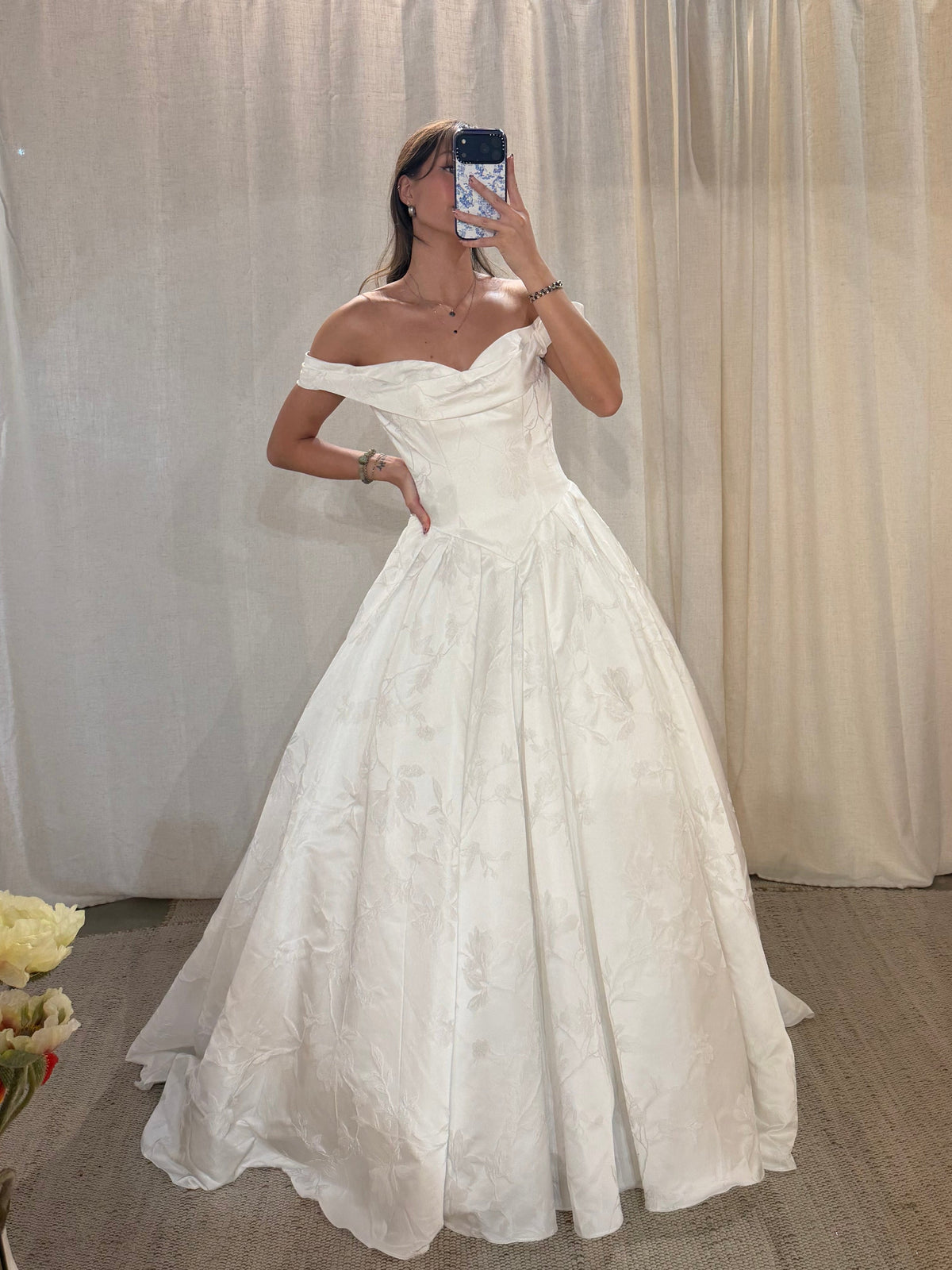 a white off-the-shoulder ball gown wedding dress with a textured, 