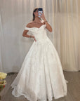 a white off-the-shoulder ball gown wedding dress with a textured, 