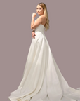 strapless white wedding gown with a fitted bodice, and a full flowing skirt with a long train.