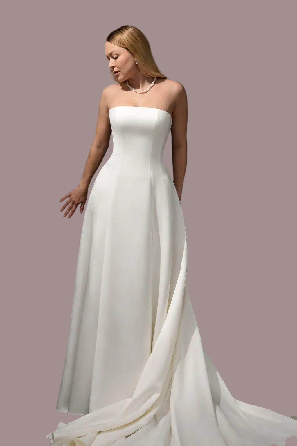 strapless white wedding gown with a fitted bodice and full flowing skirt and train against a dark studio background.