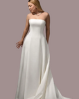 strapless white wedding gown with a fitted bodice and full flowing skirt and train against a dark studio background.
